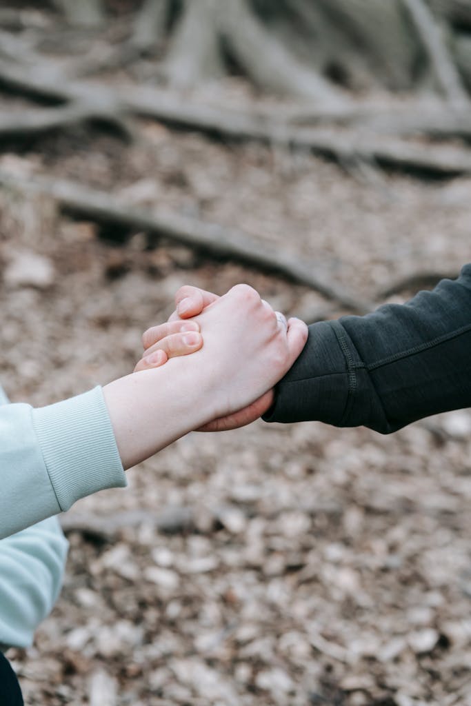 Two people holding hands in a peaceful fall forest setting, symbolizing connection and support.